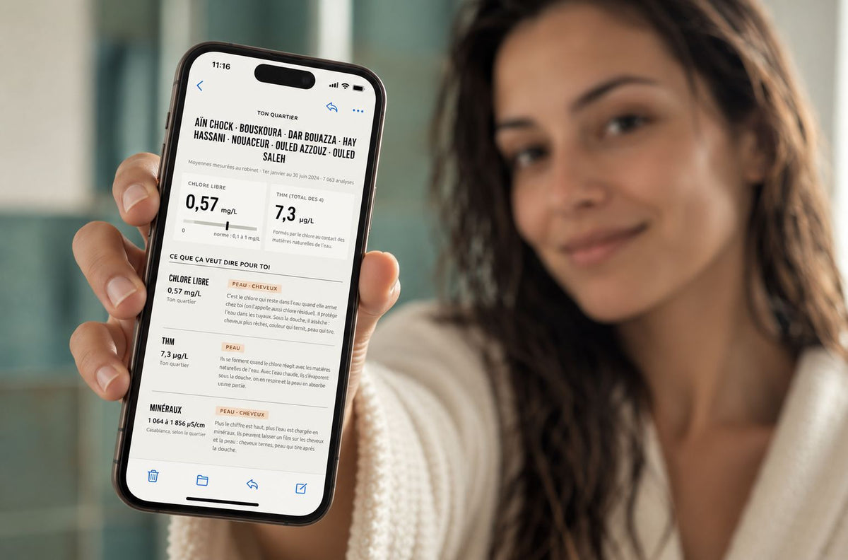 Femme souriante qui montre sur son téléphone son rapport d'eau Gloya : chlore libre, THM et minéraux de son quartier